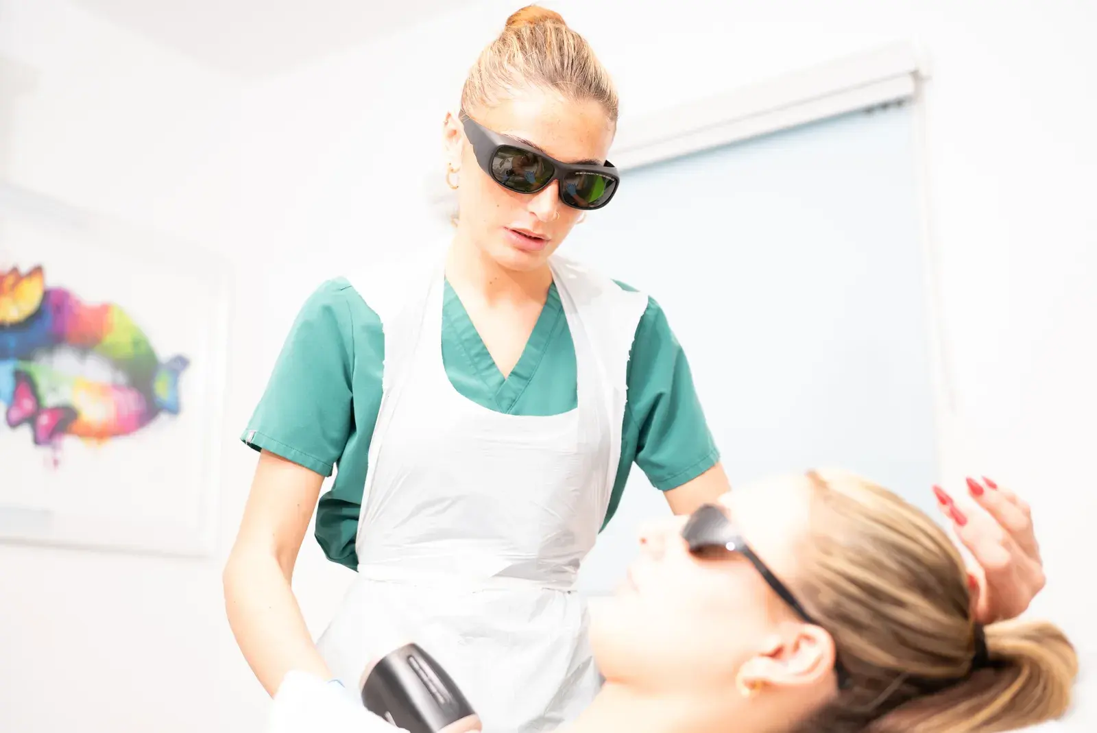 A practitioner in protective glasses uses a diode laser handpiece on a client lying on a couch