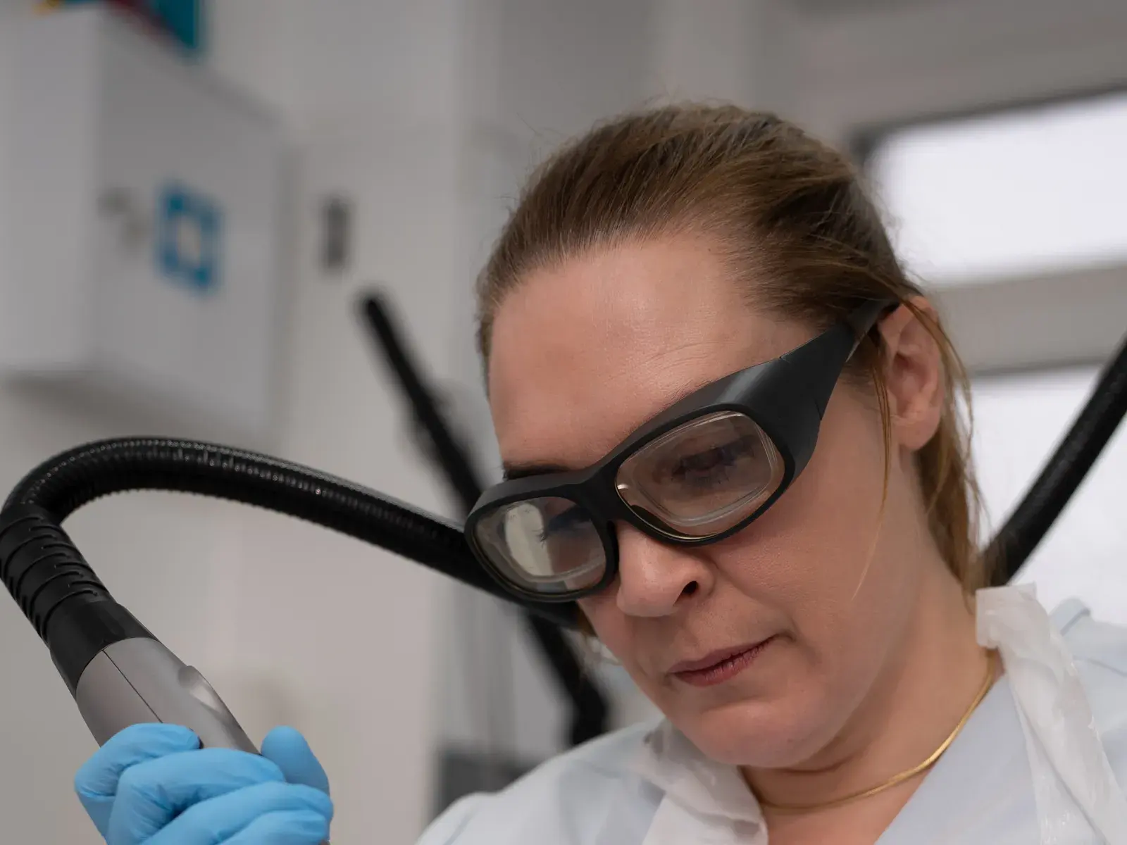 A practitioner in protective glasses holds a thulium laser handpiece